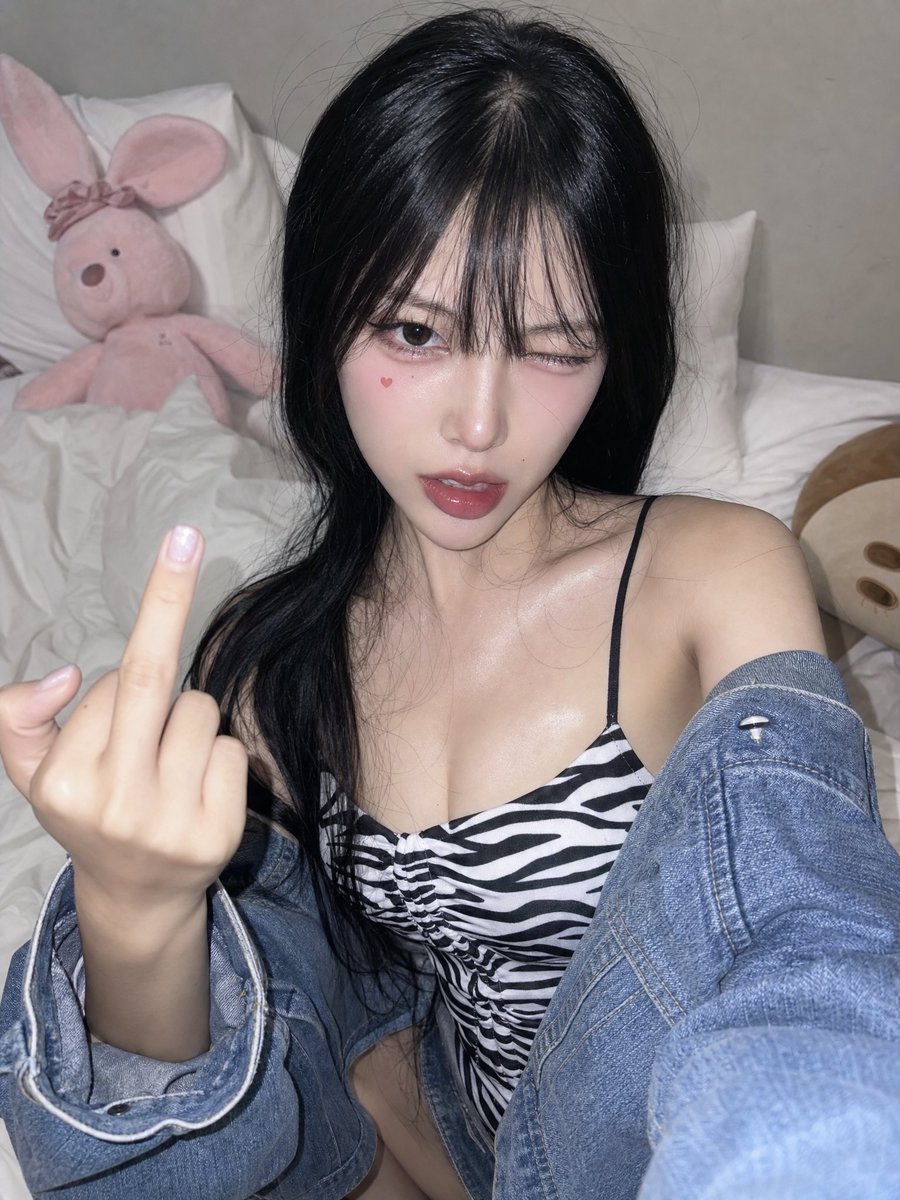 A high-angle front-camera phone selfie of a young woman in h
