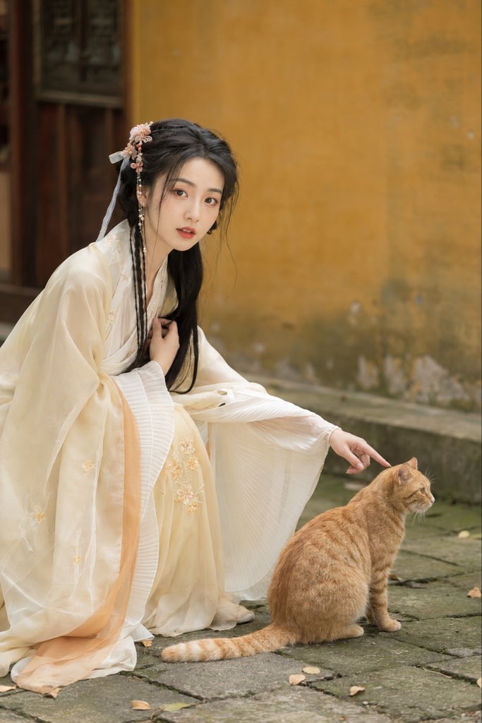 2:3 竖版真人古风户外写真,一位成年东亚女性身穿浅奶油黄与象牙白配色的轻柔古风汉服,细碎花卉刺绣,对襟结构,半透明浅色